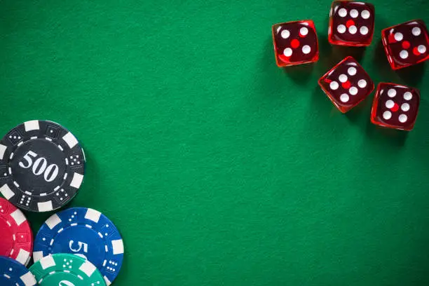 Photo of Casino chips and red dices on green empty felt