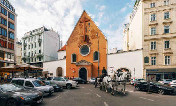 Vienna, Austria - 1 October, 2017: Horse-drawn carriage against Capuchin Church which houses Imperial Crypt on Neuer Markt square