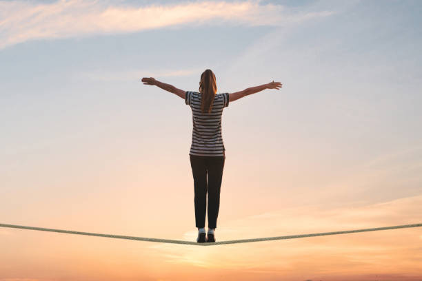 una ragazza sta sulla corda e alza le mani contro il tramonto. - tightrope balance walking rope foto e immagini stock