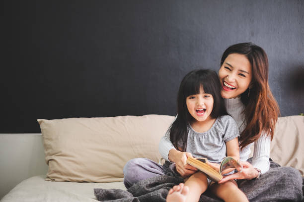 happy asian family mother and daughter on bed in bedroom say good night before sleep - baby lying down sleeping asian ethnicity imagens e fotografias de stock