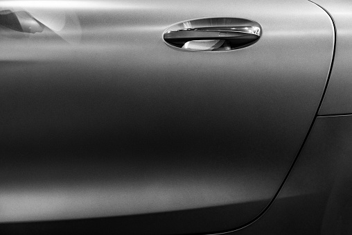 Light and shadow background of black and white car door with metallic handle.