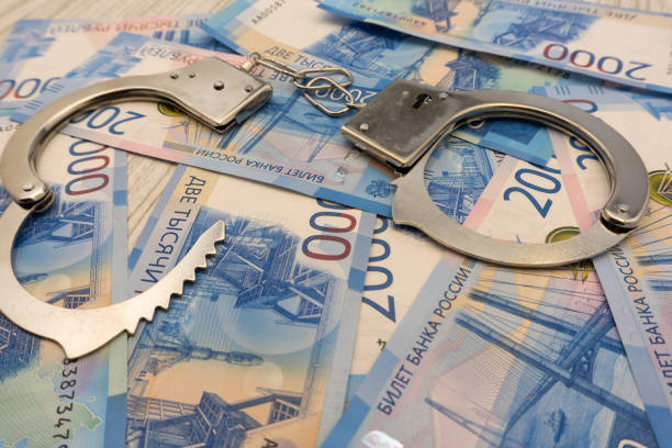 istock A pair of handcuffs close to the new stack of banknotes for 2000 rubles. Background table tree . 1092168840