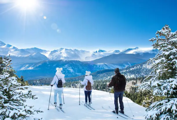 Active family skiing on winter vacation. Sun shinning on snowcapped mountain. Rocky Mountain National Park. Close to Estes Park, Colorado, USA