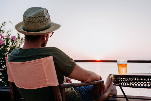istock Young man enjoying beer and sunset in a beach bar 1092171084