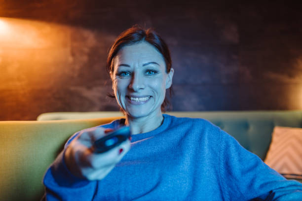 istock Woman holding remote control and watching TV 1092187110