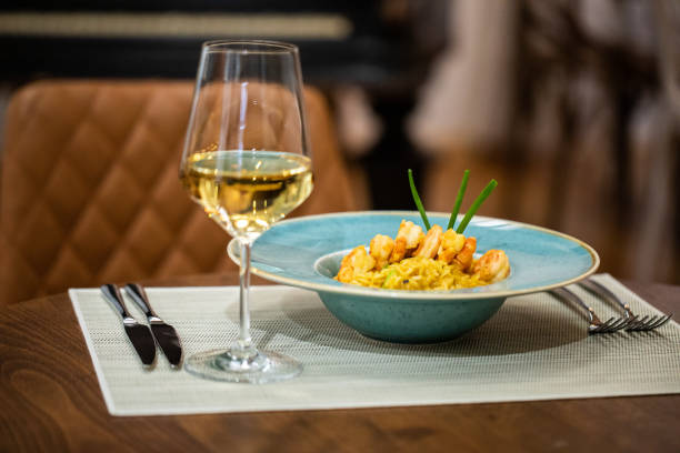Seafood risotto on plate and glass of white wine in restaurant, close up