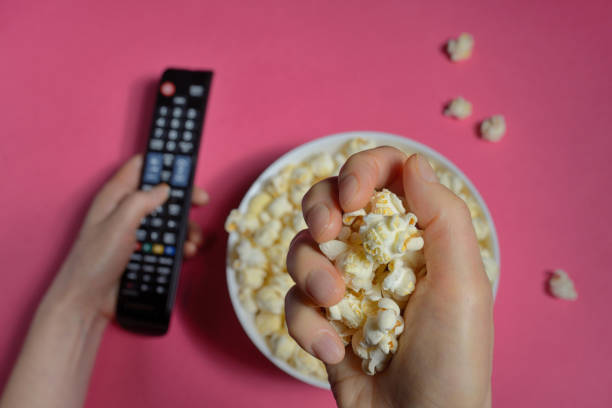 istock Top view of hands holding remote controller and popcorn bucket isolated 1092189014