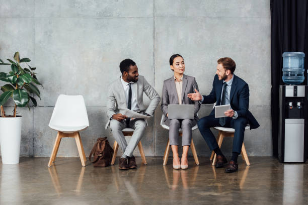 istock multicultural businesspeople sitting, using digital devices and having discussion in waiting hall 1092209998