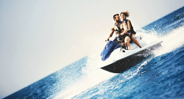 Adrenaline Junkies. Young couple jet skiing on the open sea. They are smiling and enjoying summer sport on water. jet boat stock pictures, royalty-free photos & images