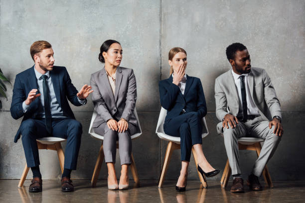 istock surprised multiethnic businesspeople sitting on chairs and looking away in waiting hall 1092216632