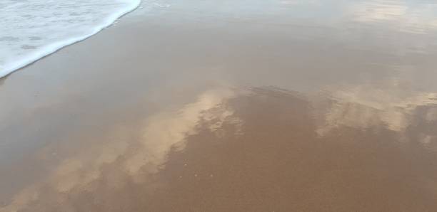 istock Frothy white sea foam arriving on sandy beach 1092229912