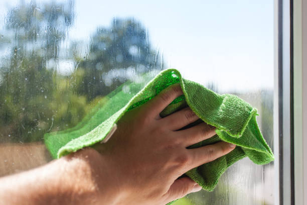 istock A man's hand washes the window with a green rag 1092236632