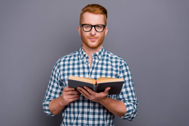 ritratto di bel contenuto sicuro bell'uomo attraente che indossa una camicia a scacchi che tiene il libro isolato su sfondo pastello grigio - professor library librarian university foto e immagini stock