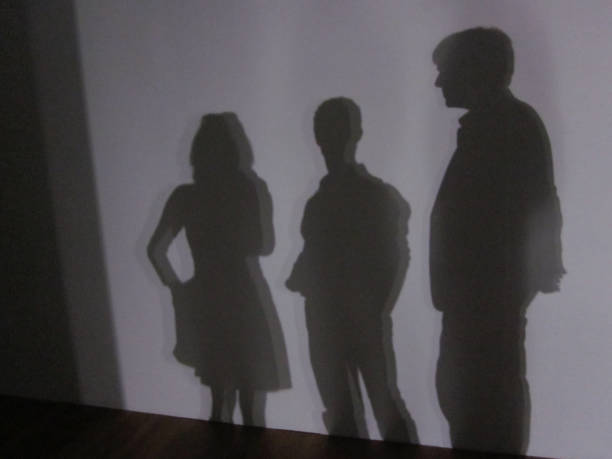 a shadow of three people standing in front of a white wall