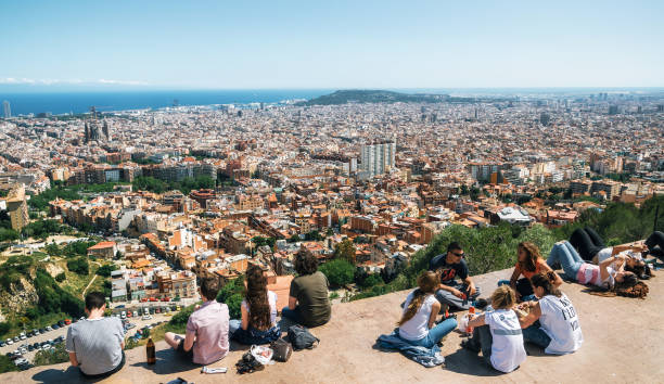 View of Barcelona, the Mediterranean sea, Sagrada Familia, Catalonia, Spain. Barcelona, Catalonia, Spain - May 30, 2015: Young people sit on the viewpoint communicate and look from the above of Barcelona city from Bunker El Carmel or Turo de la Rovira. Catalonia, Spain. parallel port stock pictures, royalty-free photos & images
