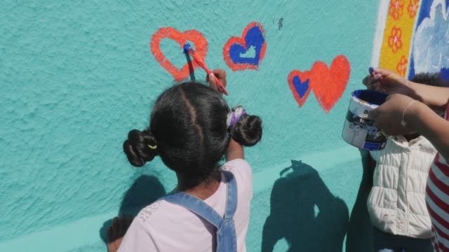 Community painting hearts mural on sunny wall