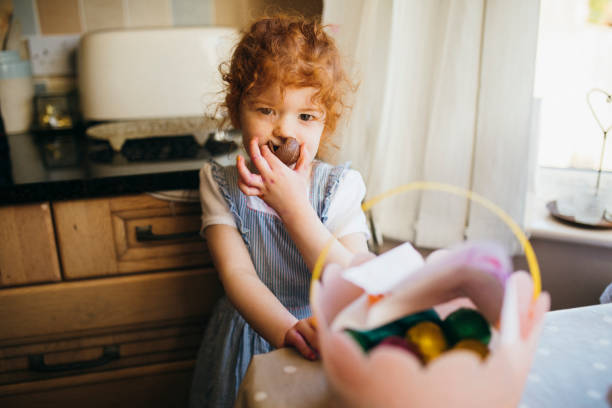 bambina che mangia un uovo di pasqua al cioccolato - easter easter egg child chocolate foto e immagini stock