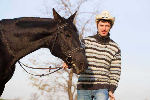 istock Man nearby horse, striped pullover, hat, smile, close up 1092260228
