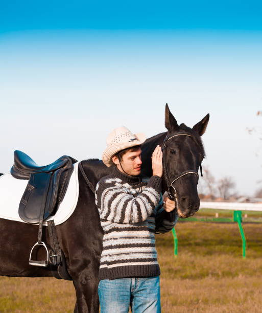 istock Man nearby horse, striped pullover, blue jeans, hat, close up 1092261264