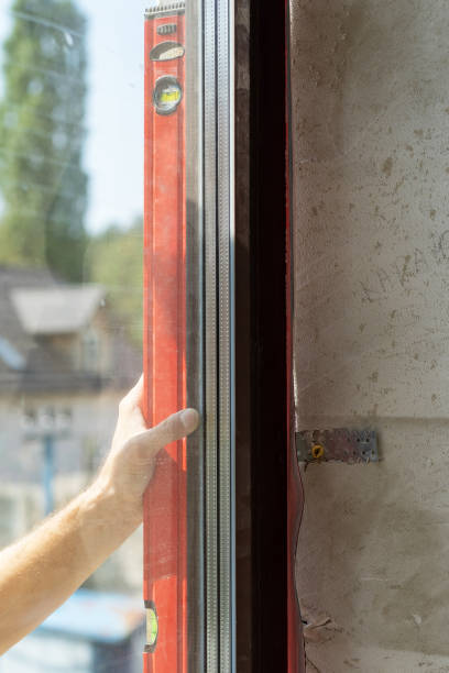 istock Plastic window installation concept. Vertical photo of mature laborer man using special instrument and checking level of new window frame 1092261276
