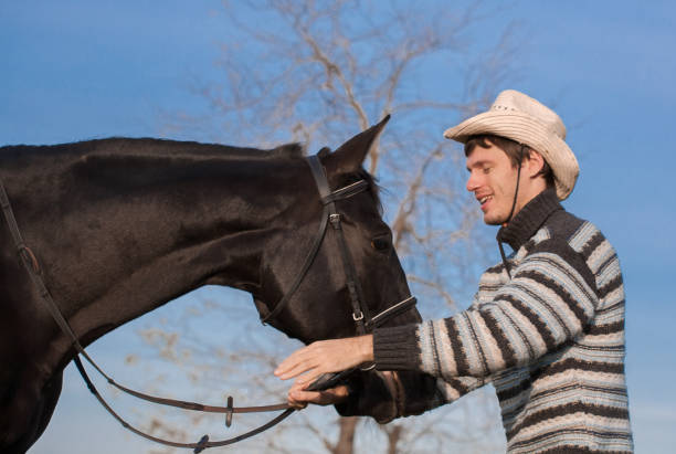 istock Man nearby horse, striped pullover, blue jeans, hat, close up 1092261324
