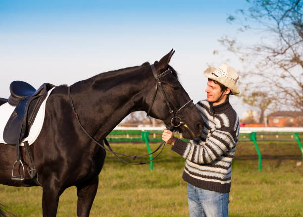 istock Man nearby horse, striped pullover, blue jeans, hat, close up 1092261602