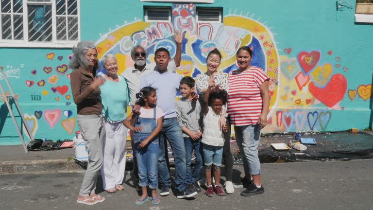 Portrait happy community clapping in front of freshly painted mural on sunny wall