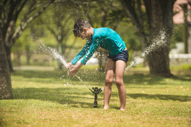 istock Boy having fun while splashing water with garden hose 1092265080