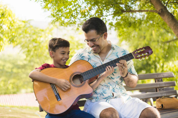 padre e figlio con una chitarra acustica - plucking an instrument foto e immagini stock