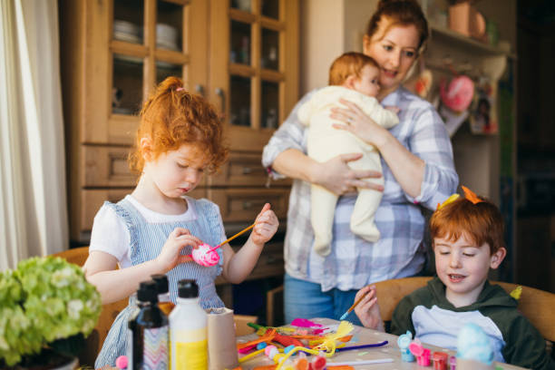 dos niños pintando huevos de pascua - familia con tres hijos fotografías e imágenes de stock