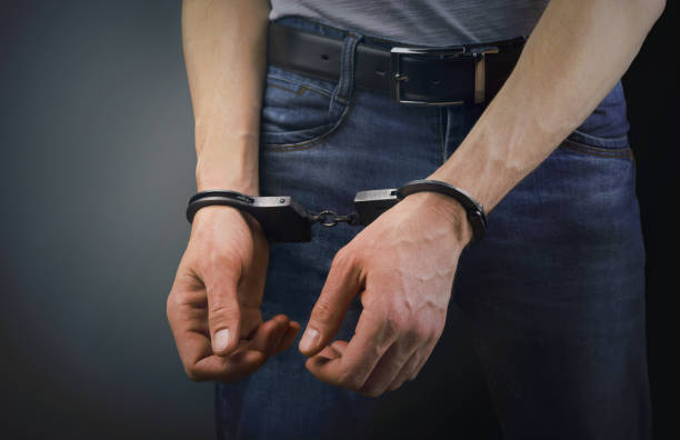 istock Arrested man in handcuffs on gray background 1092281878