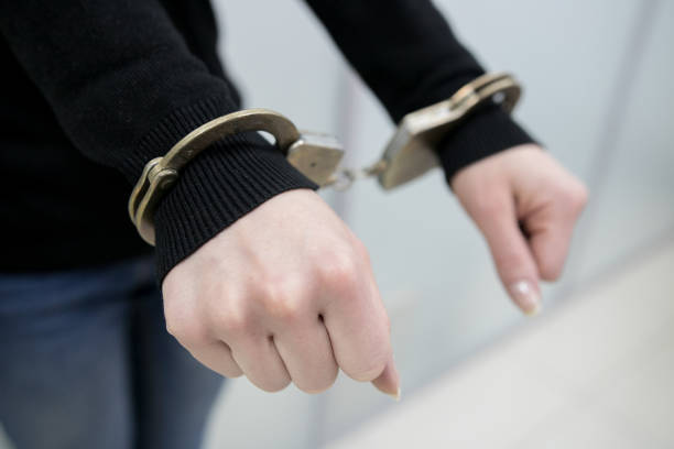 istock Close-up. Arrested man handcuffed hands at the back isolated on gray background. Prisoner or arrested close-up of hands in handcuffs. 1092288330