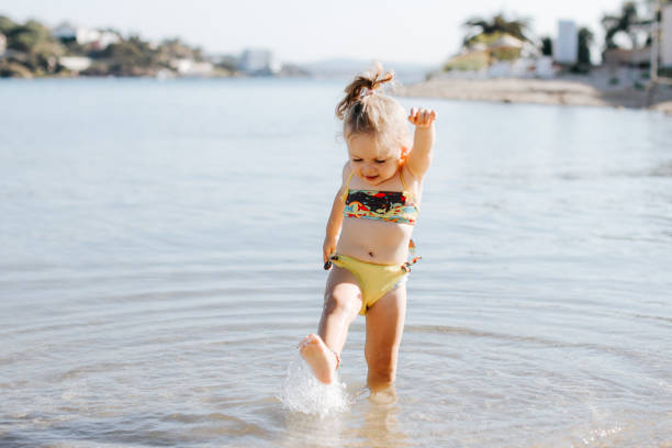 Happy laughing toddler girl having fun on sand Happy laughing toddler girl having fun on sand swimming protection stock pictures, royalty-free photos & images