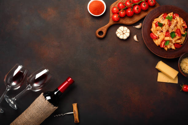 pasta with cheese, cherry tomato sauce, wineglass and bottle wine, corkscrew, garlic, turmeric on rusty background. - recipe ingredient grater cheese grater imagens e fotografias de stock