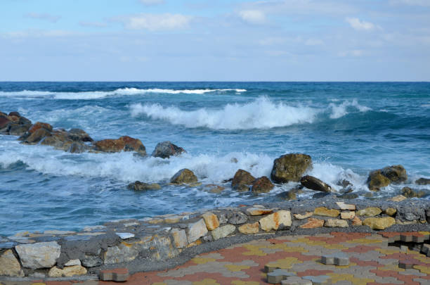 Damaged pavement in foreground and waves comming in from the sea in backgound, picture from outside the little village (Limenas Chersonisou) on Crete Island Greece.