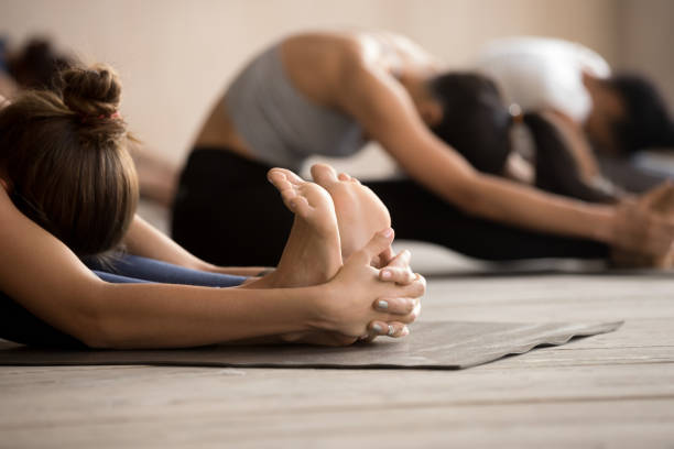 las hembras haciendo paschimottanasana sentados adelante de la curva representan - centro de yoga fotografías e imágenes de stock