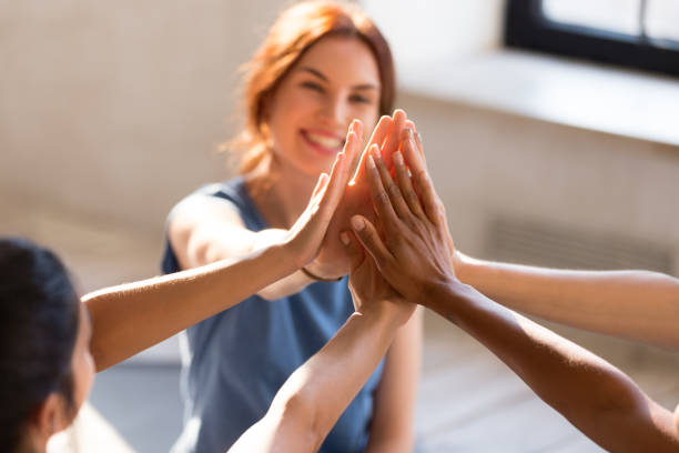 Girls giving high five, close up focus on hands Cheerful diverse young girls sitting together in sports studio before starts training giving high five feel happy and healthy, close up focus on hands. Respect and trust, celebration and amity concept gym group class stock pictures, royalty-free photos & images