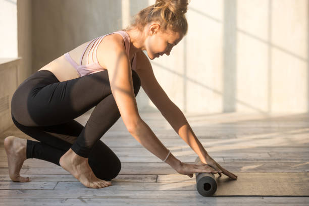 istock Young female unrolling yoga mat is preparing for session 1092303664