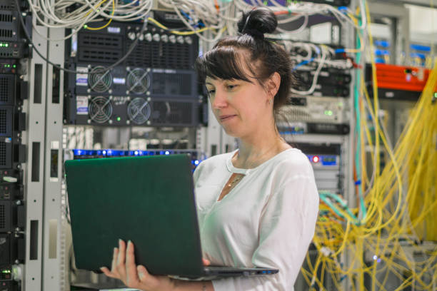 istock Programmer works on the computer in the data center.Girl with a laptop is in the server room. Woman is on the background of powerful servers. Selective focus 1092306602