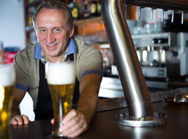 istock Smiling barman is offering unbottled beer to next client 1092308988