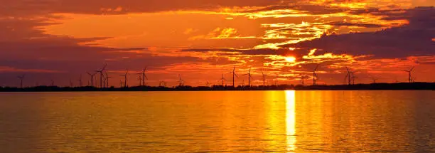 Wind turbine, wind power sun reflection over Lake Ontario red