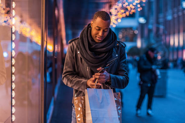 Handsome black man at Christmas Shopping Handsome brunette black male tourist enjoying winter shopping in the high street holiday shopping stock pictures, royalty-free photos & images