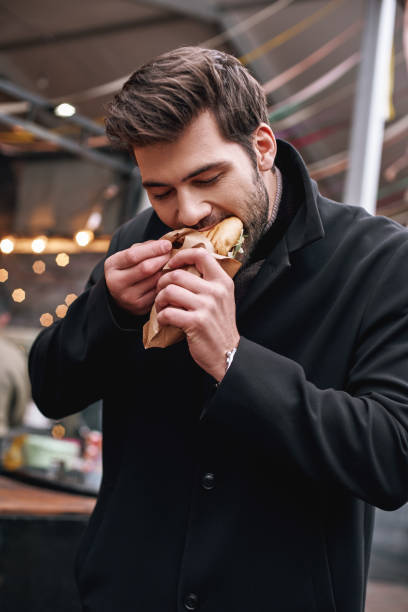 jeune homme élégant, manger à l’extérieur "sandwich" au bar "sandwich" - client satisfait humour photos et images de collection
