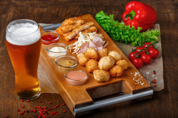 istock Big set of snacks for beer it includes fried cheese balls, pigtail cheese, ham and crab sticks on a wooden board 1092355612