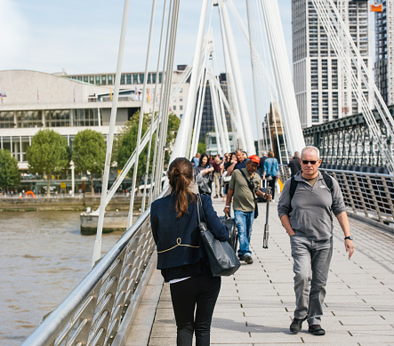 London: Pedestrians walking on a warm sunny day on the Hungerford Bridge in London