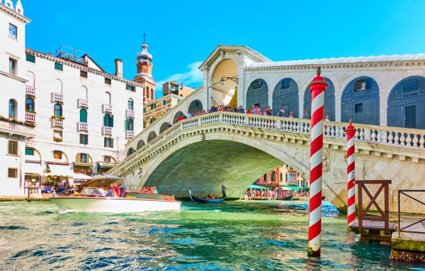 Rialto Bridge in Venice The Rialto Bridge in Venice on sunny summer day, Italy. Boat and people on the bridge a bit in motion blur! grand canal venice stock pictures, royalty-free photos & images