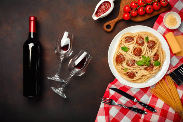 spaghetti pasta with meatballs, cherry tomato sauce, cheese, wineglass and bottle on rusty background. - foods and drinks clothing garment household equipment imagens e fotografias de stock