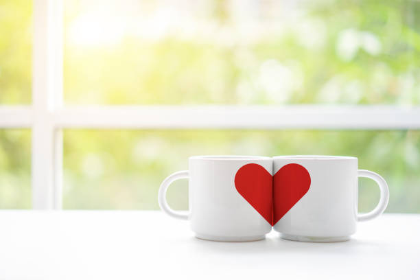 Mugs cups of coffee or tea for two lovers honeymoon wedding morning in coffee shop with green nature in background. Copy space with white wooden table. Valentines day concept. Mugs cups of coffee or tea for two lovers honeymoon wedding morning in coffee shop with green nature in background. Copy space with white wooden table. Valentines day concept. mug photos stock pictures, royalty-free photos & images