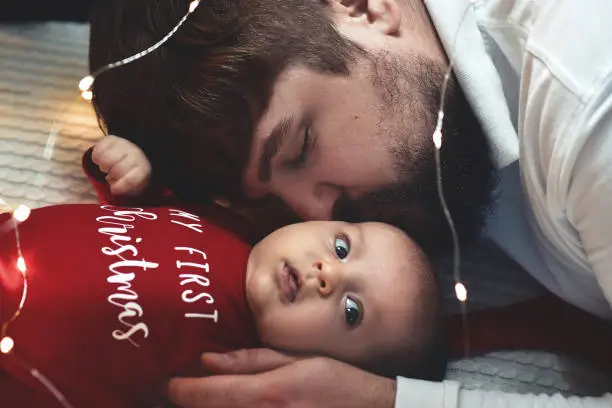 Photo of Man with baby. Young muscular man holding baby and kissing her.