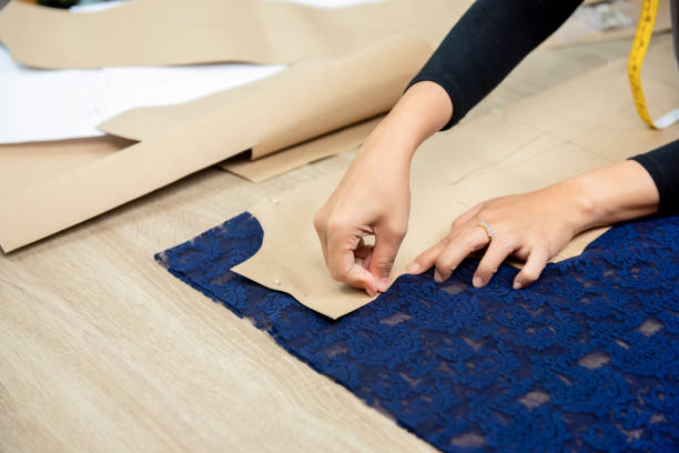 istock Designer hands pinning paper pattern on fabric at the table 1092392394